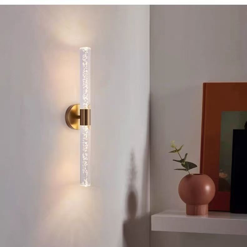 Natural copper wall sconce lit on a wall beside a plant