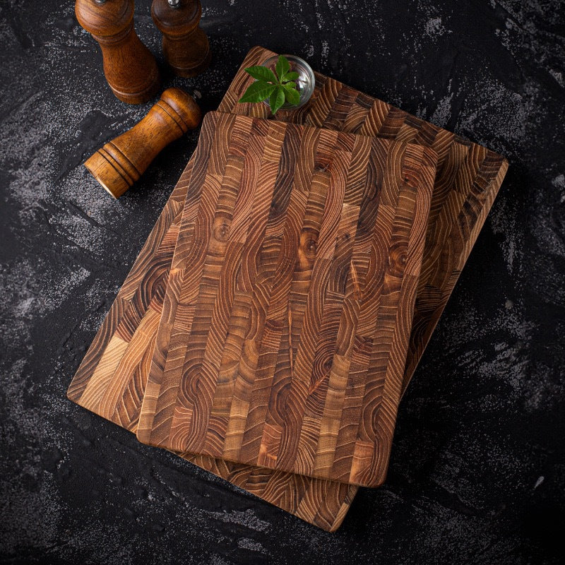 Two end-grain teak cutting boards stacked on a dark stone counter