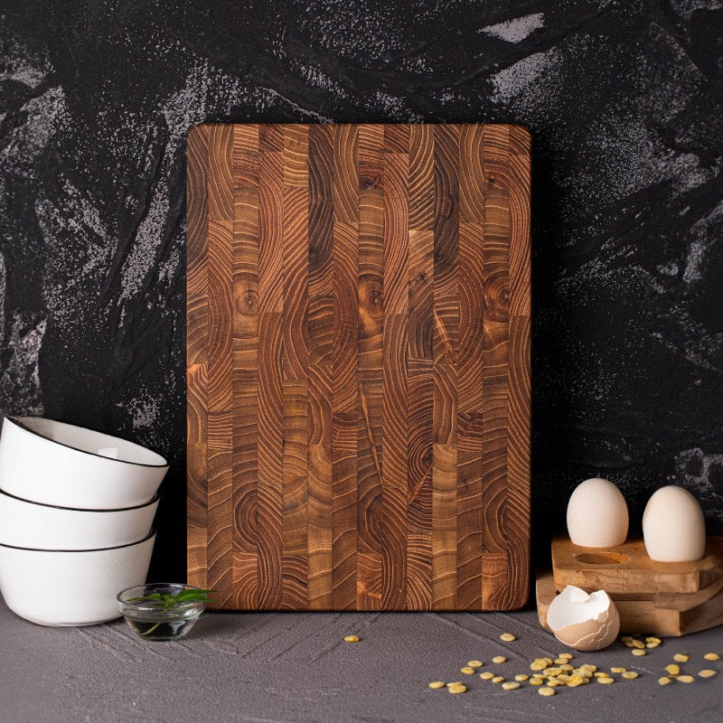 End-grain teak cutting board with bowls and eggs on a dark counter