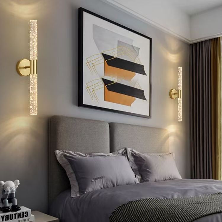 Wall sconce lit in a bedroom beside framed art
