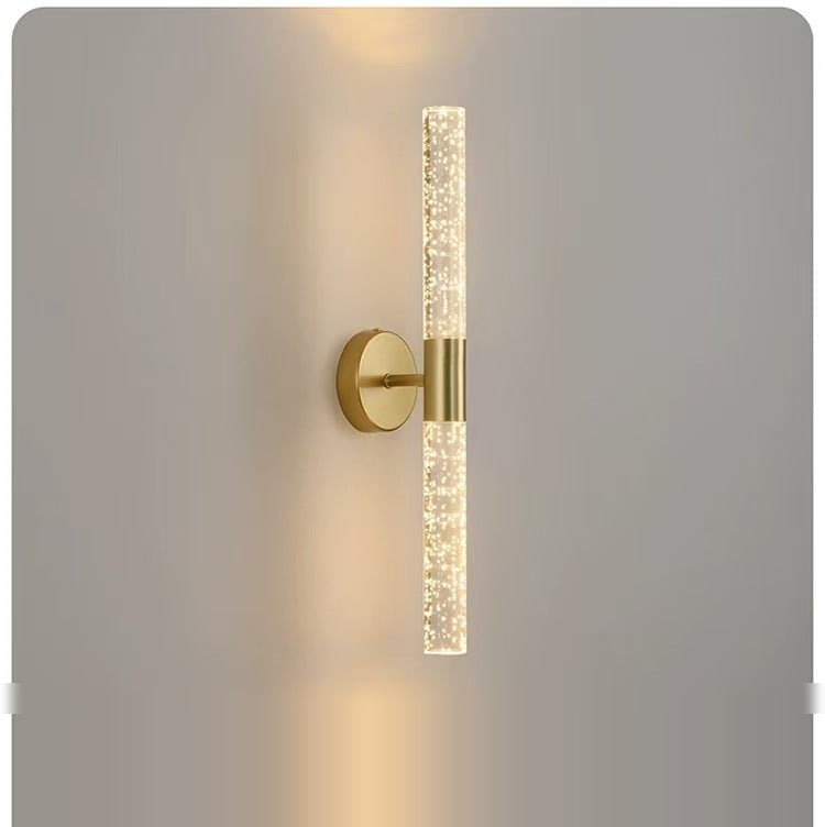 LED wall sconce in natural copper, slim vertical bubble-texture tube on a round plate, lit