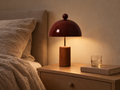 Wood base table lamp glowing on a bedside table