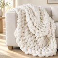Creamy white chunky knit throw draped over a linen sofa