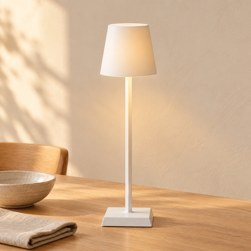 White cordless aluminum table lamp lit on an oak dining table
