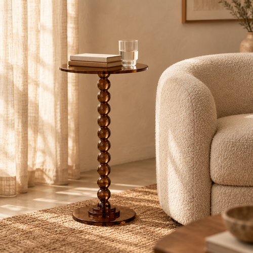 Smoke brown acrylic pedestal side table next to a boucle armchair in a reading corner