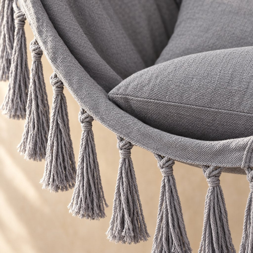 Close view of the light grey canvas weave with its knotted tassel fringe and a cushion corner